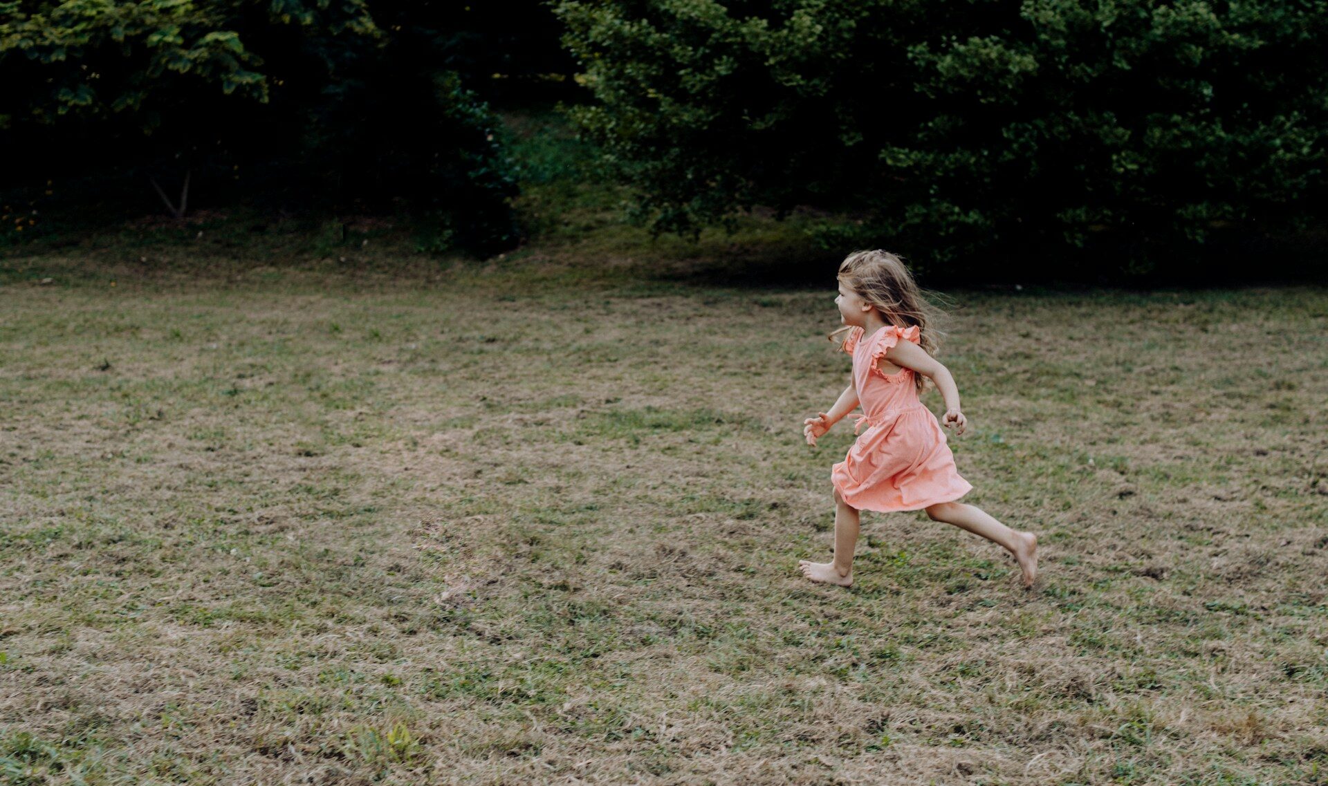 A little girl running across a grass covered field