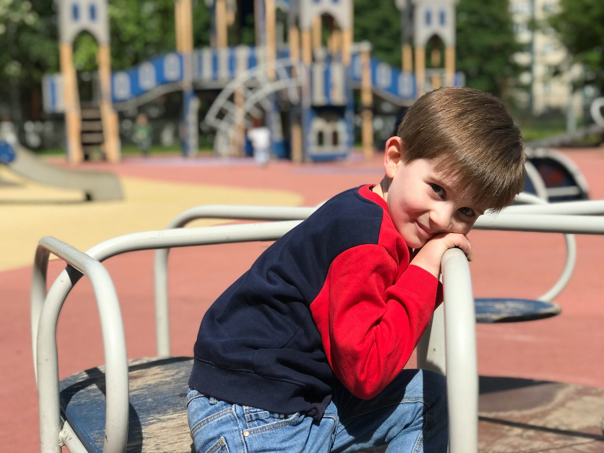 a young boy sitting on top of a metal bench