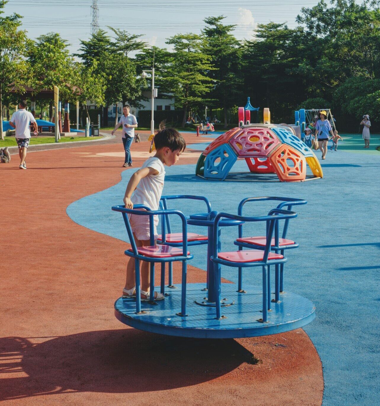 woman in white t-shirt sitting on blue metal chair near body of water during daytime