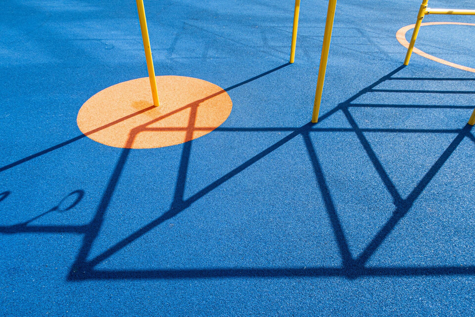 A playground with a blue ground and yellow poles